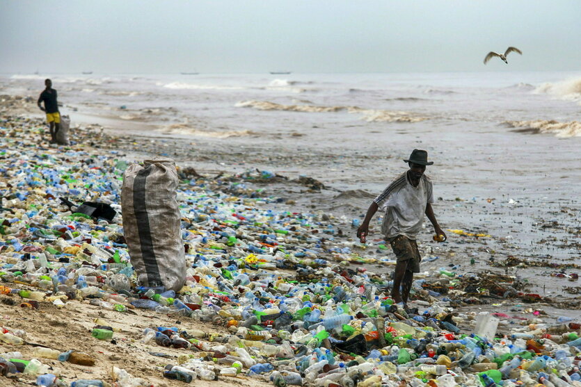Menschen laufen über Plastikmüll am Strand