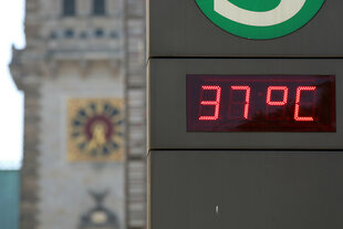 Temperaturanzeige 37 Grad auf einer S-Bahn-Stele vor dem Hintergrund des Hamburger Rathausturms
