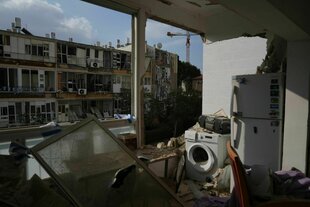 Eine Waschmaschine, beschienen von der Sonne, die durch eine weggesprengte Wand in die Ruine scheint