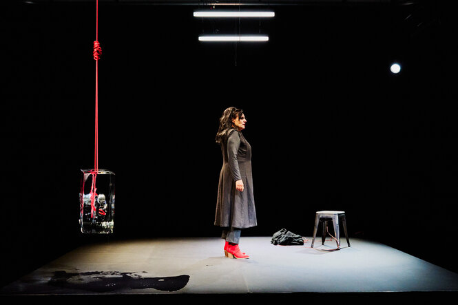 Die Theaterbühne: links hängt das Maschinengeweht im Eis, in der Mitte steht die Schauspielerin Susanne Jansen in der Rolle der Gudrun Ensslin