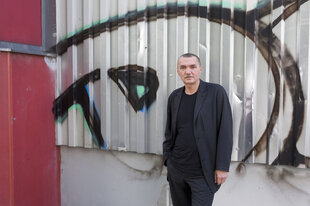 Wolfgang Engler vor einer Wellblechwand mit Graffiti