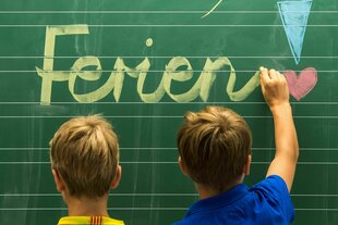 Zwei Kinder stehen vor einer Schultafel