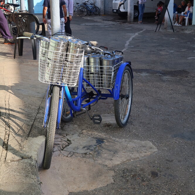 Ein Fahrrad mit Anhänger, auf dem viele Essensbehälter sind