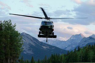 Ein Hubschrauber fliegt vor einer Bergkette