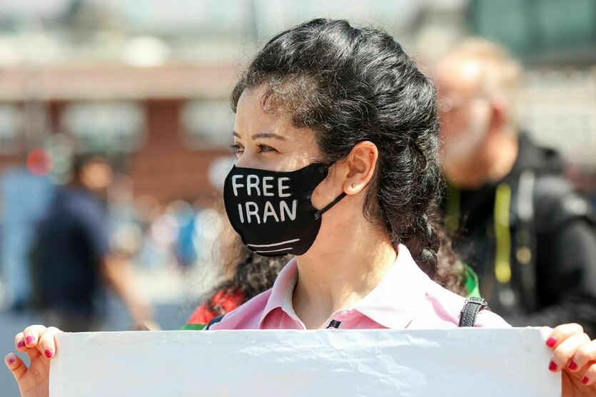 Eine Frau auf einer Demonstration trägt eine Maske mit der Aufschrift „Free Iran“