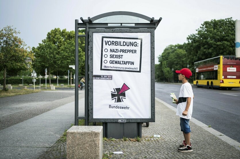 Ein Junge mit Basecap steht vor einem Werbeplakat