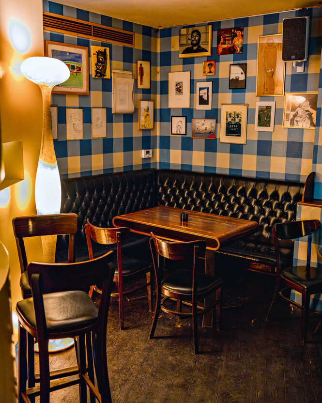 Ein Raum in warmem Licht, Holzmöbel vor einer bilderverzierten blau-weißen Wand