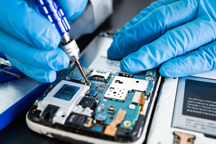 Hände schrauben an einem geöffneten Smartphone