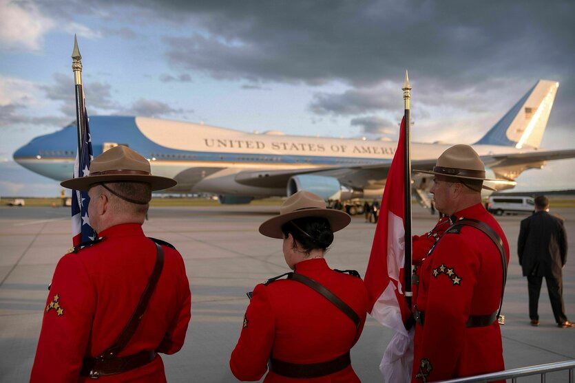 Drei rot-Uniformierte stehen vor der Air Force One auf einem Rollfeld