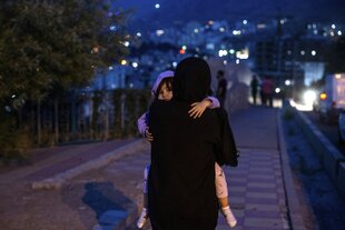 Eine Frau trägt ein Kind auf dem Armi und geht durch die Nacht