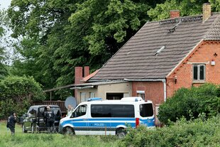 Ein Polieiwagen steht vor einem alten Einfamilienhaus im Grünen