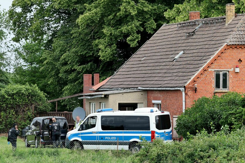Ein Polieiwagen steht vor einem alten Einfamilienhaus im Grünen