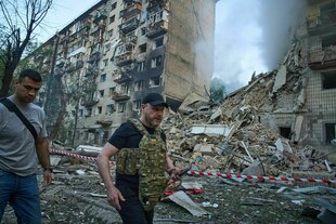 Zerstörter Wohnblock, davor mit Schutzweste der ukrainische Innenminister Ihor Klymenko