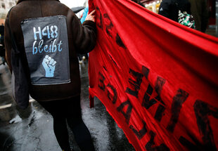 Eine Teilnehmerin trägt ein Schild mit der Aufschrift „H48 bleibt“ auf dem Rücken bei einer Demonstration von einem Bündnis von Mieterinitiativen.
