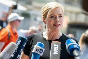 Julia Klöckner spricht in Pressemikrofone, das Gesicht scheint hart.