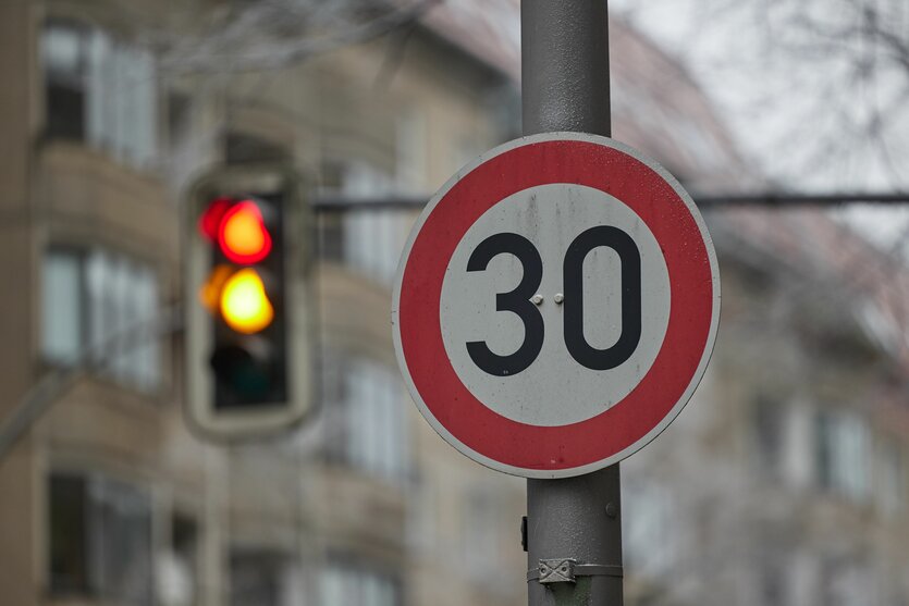Das Foto zeigt zeigt ein "Tempo 30"-Schild mit einer Amepl im Hintergrund