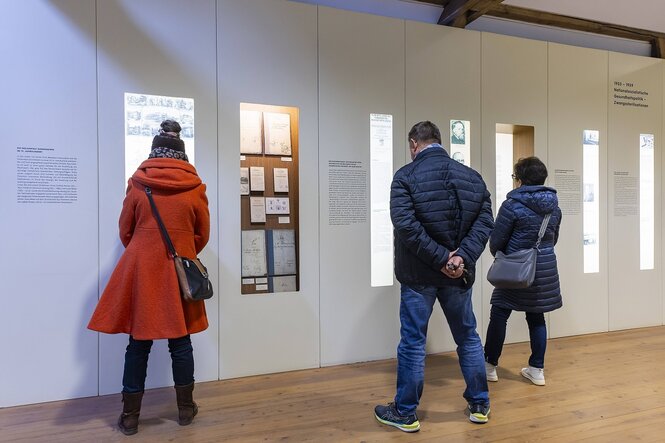 Menschen schauen sich SChautafeln in der gedenkstätte Pirna Sonnenstein an