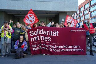 Eine Gruppe von Menschen steht mit einem Transpi mit der Aufschrift 