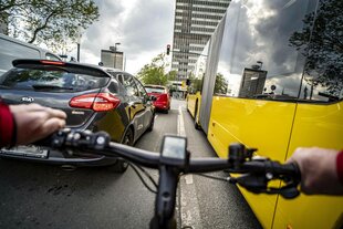 Blick über den Lenker eines Radfahres in den dichten Autoverkehr