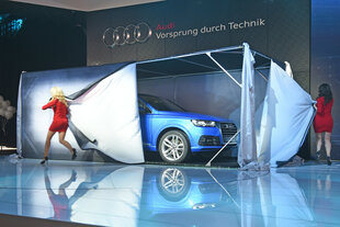 Zwei Frauen in Miniröcken enthüllen ein neues Auto bei einer Automesse.