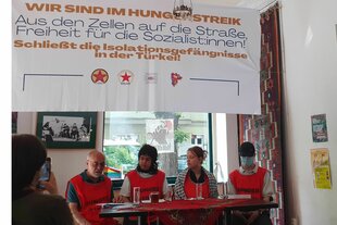 Vier Personen sitzen mit roten Westen an einem Tisch