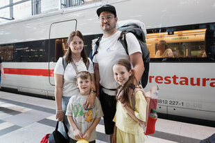 Eine Familie mit Kindern vor einem ICE der Bahn.