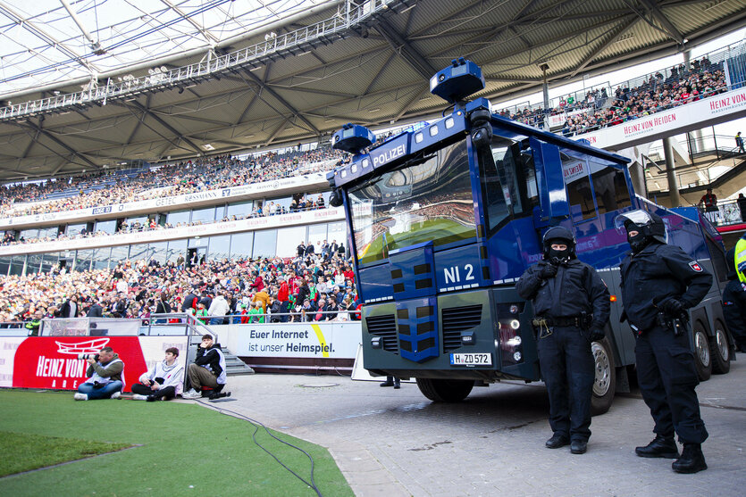 Die Polizei mit Wasserwerfer im Innenraum eines Fussballstadions