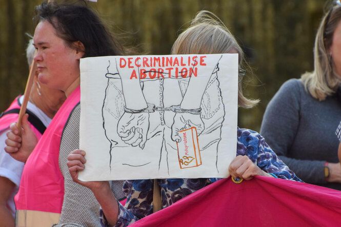 Eine Frau fordert auf einem Schild das Ende der Kriminalisierung von Abtreibungen