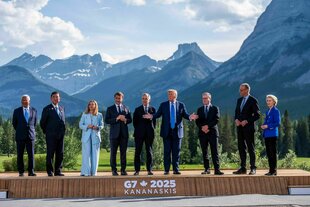 Neun Männer und Frauen stehen auf einem Podest für ein Foto vor der Kanadischen Bergwelt