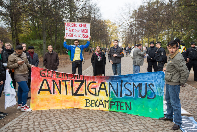 Menschen auf einer Straße halten ein buntes Transparent mit der Aufschrift "Antiziganismus stoppen".