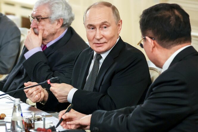 Der russische Präsident Wladimir Putin im Gespräch mit einem Sitznachbarn