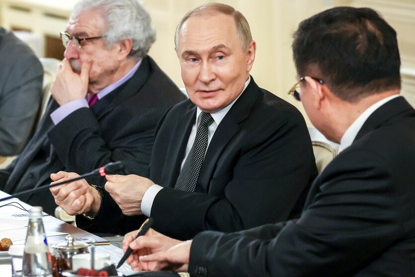 Der russische Präsident Wladimir Putin im Gespräch mit einem Sitznachbarn