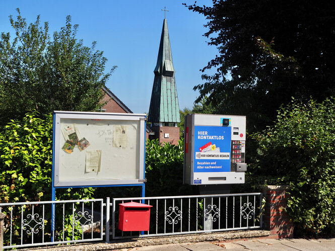 Eine Straßenszene, Kirchtum und Zigarettenautomat.