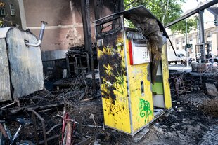 Verkohlte Holzreste und ein abgebrannter Fotoautomat im Biergarten der Renate