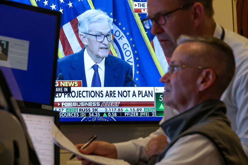 Börsenmakler vor einem Bildschirm, der Notenbankschef Jerome Powell zeigt