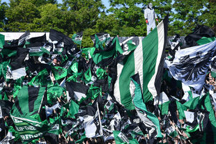 Fußballfans von SC Preußen Münster schwenken Fahnen im Stadion
