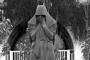 Eine Statue zeigt einen weinende Person.