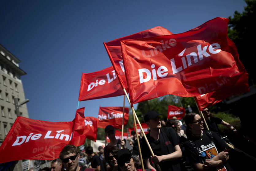 Das Bild zeigt Menschen mit roten Fahnen, die den Schriftzug "Die Linke" zeigen