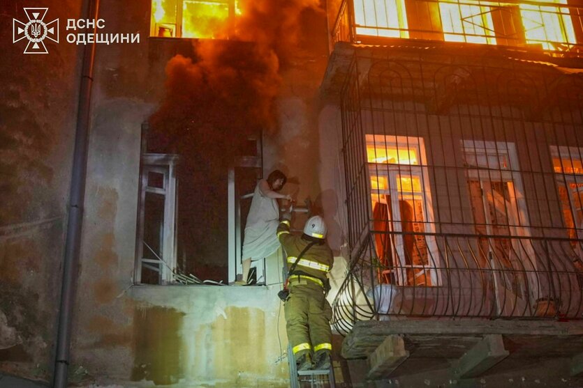 Feuerwehrleute retten eine Bewohnerin aus einem brennenden Wohnhaus
