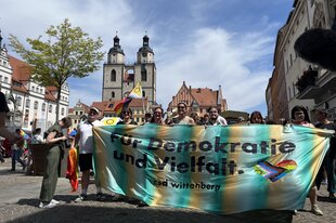 Menschen halten einen Banner mti der Aufschrift 