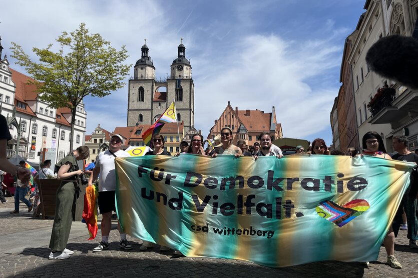 Menschen halten einen Banner mti der Aufschrift "Für Demokratie und Vielfalt"