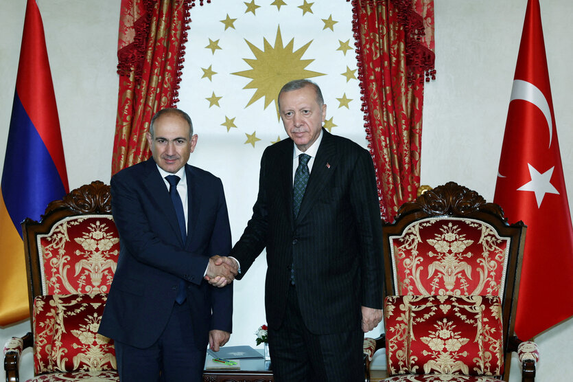 Zwei Männer geben sich vor armenischer und türkischer Fahne die Hand