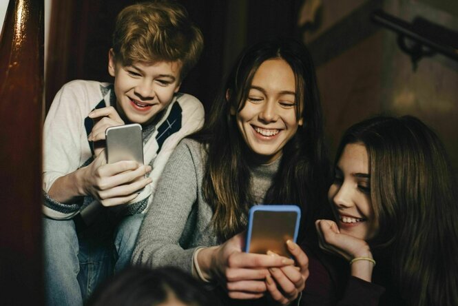 Jugendliche sitzen auf einer Treppe und schauen in ihre Handy