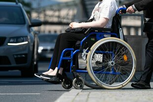 Eine Frau im Rollstuhl am Straßenrand