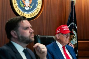 Trump sitzt mit roter Kappe neben J.D. Vance