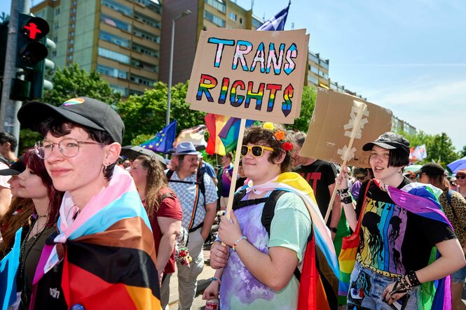 Eine Person, die ein Plakat mit der Aufschrift Trans Right! hochhält