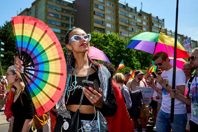 Eine Person mit einem großen Handfächer mit Regenbogenmotiv