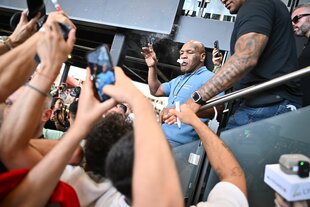 Der Boxer Mike Tyson raucht einen Joint, um ihn herum stehen Menschen die das mit ihren Handys filmen
