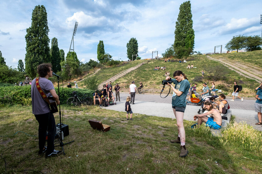 Berlin Mauerpark, junge Menschen lauschen einem Musiker