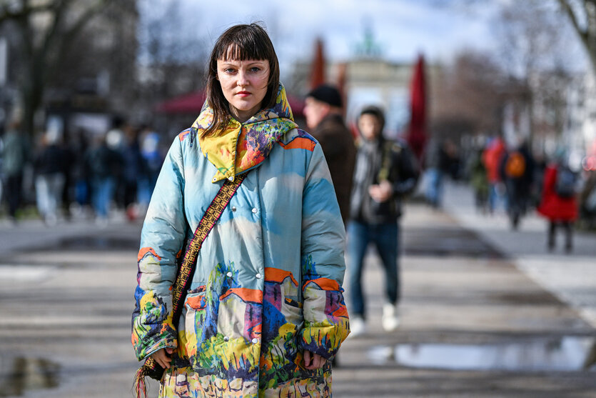 Eine Frau in bunter Jacke schaut ernst in die Kamera